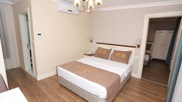 A neatly arranged bedroom with a bed, bedside tables, and a chandelier.