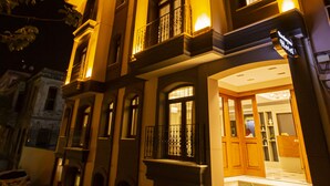 A multi-story building with a well-lit entrance, large windows, and a visible staircase leading to the entrance. - Haci Bayram Hotel (Istanbul)