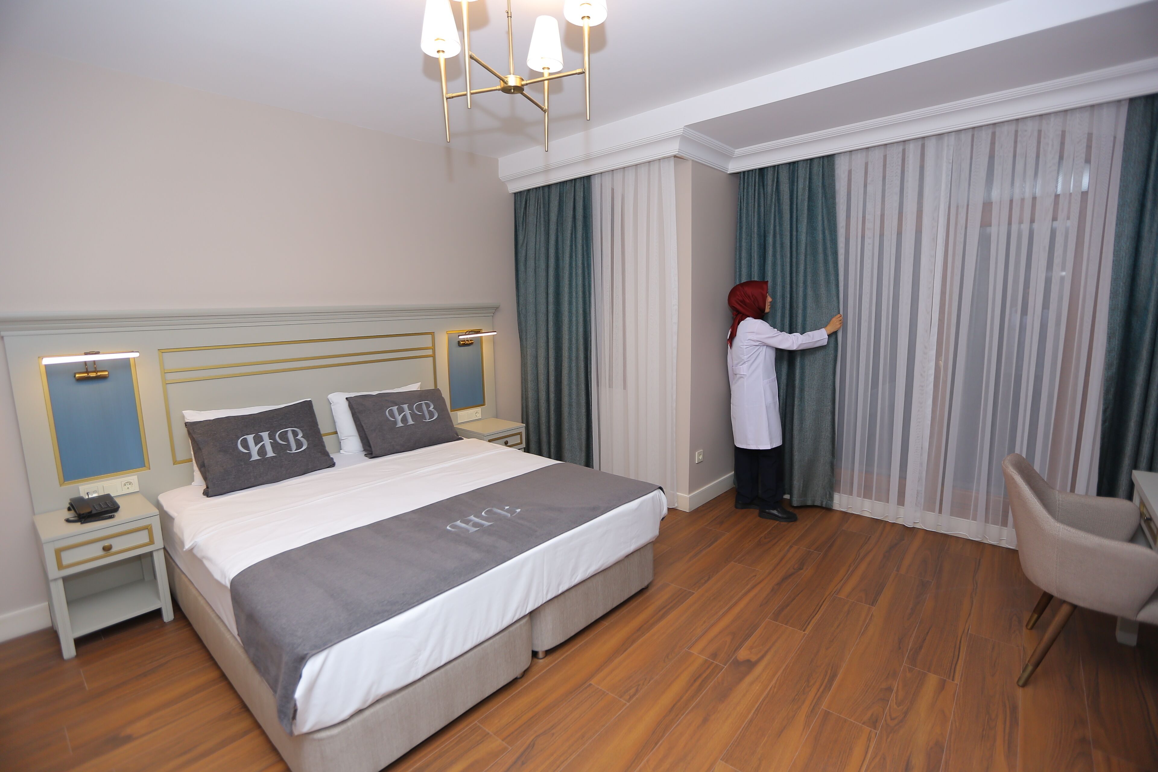 A hotel room with a bed, a nightstand, a chair, and a window with curtains.