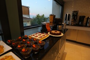 A kitchen counter with a variety of desserts, including a chocolate cake and several small chocolate cups with strawberries.
