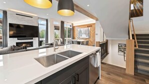 Een moderne keuken met een groot kookeiland, inbouwapparatuur en hanglampen.