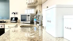 A modern kitchen with granite countertops, a built-in oven, a microwave, and a bread box labeled "BREAD". - Sight Flat - SF01 - One Bedroom Flat (London)