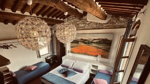 A cozy bedroom with a bed, two seating areas, a desk, and a large painting. - Olimagio Farmstay w/animals & 25m pool <4km Forte dei Marmi beach (Pietrasanta)