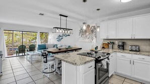 Una cocina moderna con armarios blancos, encimera de granito y electrodomésticos de acero inoxidable.