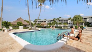 Una piscina con sillones de descanso y palmeras.