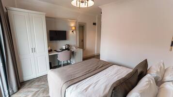 A hotel room with a bed, a desk, a chair, a television, and a wardrobe.
