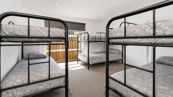 Une chambre avec des lits superposés, une porte en bois et une vue sur un balcon.