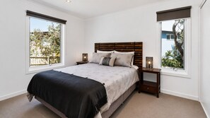 Un dormitorio con cama, mesitas de noche y ventana.