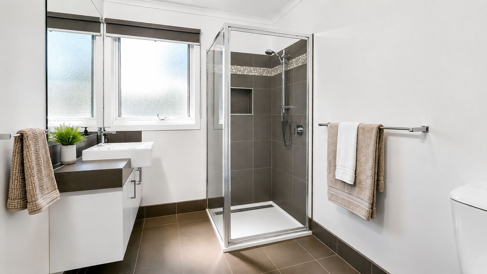 A modern bathroom with a shower, a sink, and a toilet.