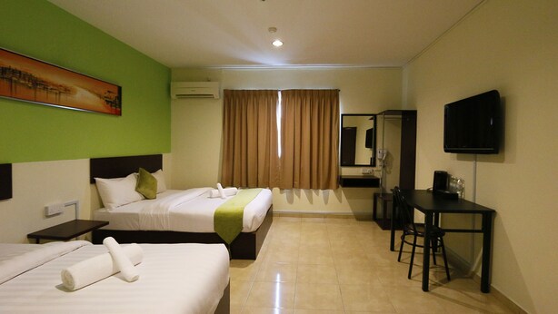 A hotel room with two beds, a desk, a chair, a television, and a painting on the wall. - Golden Roof Hotel Falim Ipoh (Ipoh)