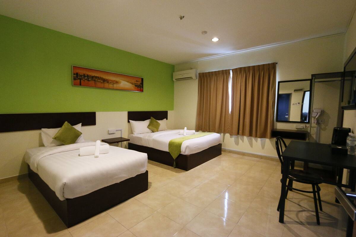 A hotel room with two beds, a desk, and a chair.