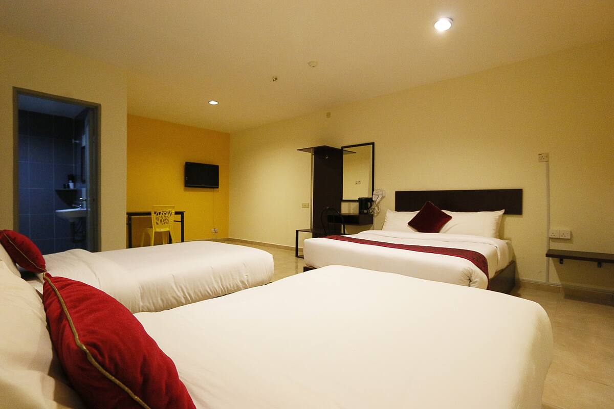 A hotel room with two beds, a TV, a mirror, and a small table.