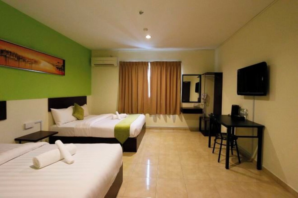 Habitación de hotel con dos camas, un escritorio, una silla, un televisor de pantalla plana y una ventana con cortinas.