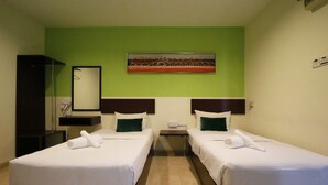 A hotel room with two single beds, a green wall, a painting, a mirror, and a nightstand with a phone. - Golden Roof Hotel Falim Ipoh (Ipoh)