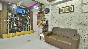Una sala de estar con un sofá, una mesita, una pared decorativa con un reloj y un televisor.