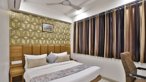 Una cama bien hecha con una colcha estampada, un cabecero de diseño geométrico y una ventana con cortina.