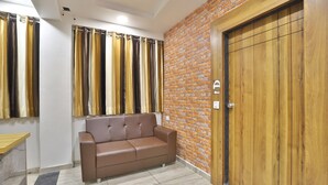 Una habitación con un sofá de cuero marrón, una puerta de madera y una pared de ladrillo.