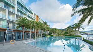 Ein modernes Hotel mit Pool, Palmen und Blick auf das Wasser.