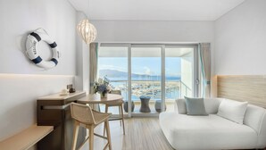 Ein modernes Hotelzimmer mit Balkon, einer Couch, einem Schreibtisch und einem Sessel.
