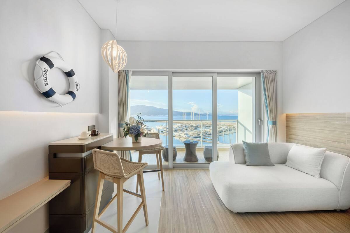 Una habitación de hotel moderna con balcón, sofá, escritorio y silla.