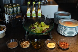 A kitchen counter with a glass bowl of salad, various condiments, and stacked plates.