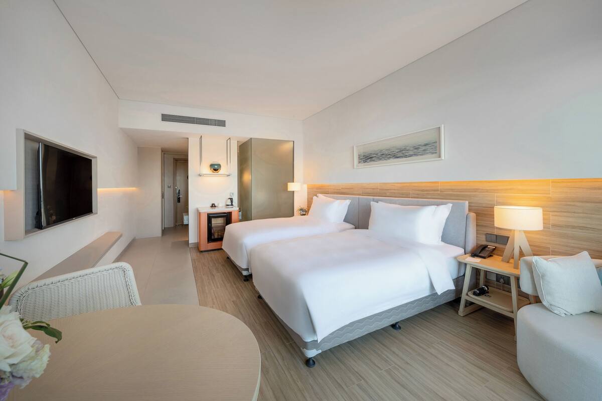 Una habitación de hotel con una cama grande, televisión, escritorio y una silla.