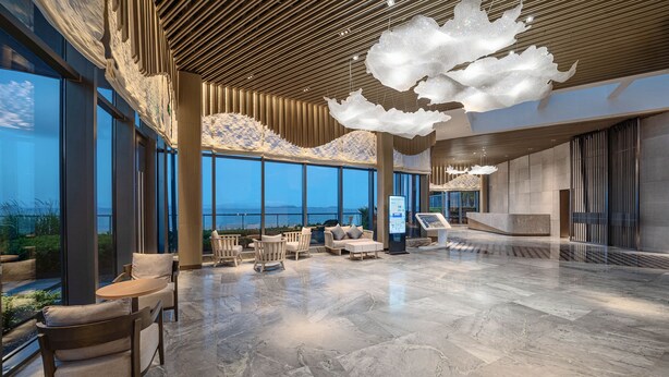 Eine geräumige Lobby mit hoher Decke, großen Fenstern und Meerblick.