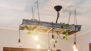 A kitchen with a central island, wooden cabinets, and hanging pendant lights. - Ananda Eco House - Rainforest Retreat (Montville)