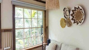 A cozy room with a sofa, a hanging light fixture, and decorative wall art. - Ananda Eco House - Rainforest Retreat (Montville)