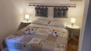 A bedroom with a bed, two bedside tables, two lamps, and a quilt.