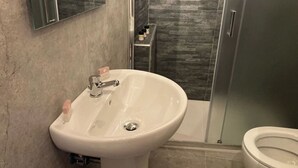 A bathroom with a white sink, a toilet, and a glass shower enclosure.