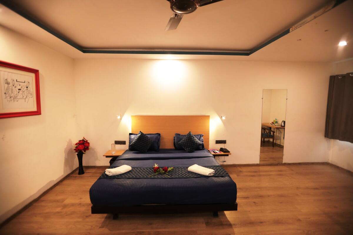 A bedroom with a large bed, bedside tables, a ceiling fan, and a framed picture on the wall.