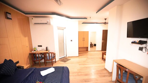 Een hotelkamer met een bed, een bureau, een stoel, een televisie en een kitchenette.