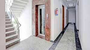 Een modern interieur met een trap, een deur met een marmeren afwerking, een brandblusser en een gestreept plafond.