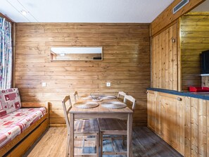 A wooden interior with a dining table, chairs, a sofa, and a kitchen area. - Bright renovated studio · Sleeps 4 · South/west balcony (Les Arcs 1800)