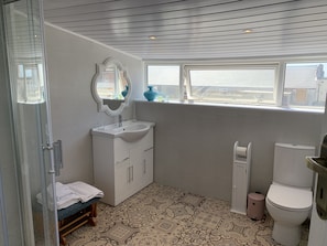 A bathroom with a shower, sink, toilet, and a window with a view. - Heather Glen 6 Bedroom 6 Bathroom Home by the sea (Blackpool)