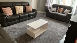 A living room with two leather sofas, a white coffee table, and a grey carpet.
