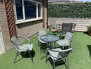 A patio with a table and four chairs, a window, and a hedge. - Heather Glen 6 Bedroom 6 Bathroom Home by the sea (Blackpool)