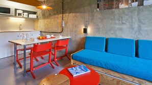 A modern kitchen with a dining area, a blue sofa, and a red table.