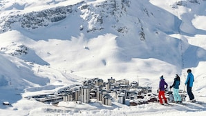 Una montagna innevata con una stazione sciistica e degli edifici in primo piano.