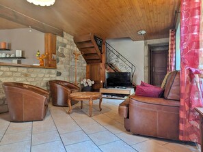Ein Wohnzimmer mit Ledermöbeln, einer Steinwand, einer Holzbalkendecke und einer Treppe.