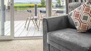 A living room with a large sliding glass door leading to an outdoor deck. - 1 bedroom accommodation in Laurenkirk (Laurenkirk)