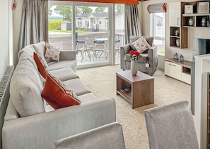 Una sala de estar moderna con un sofá, sillones, una mesa de centro y un mueble para la televisión.