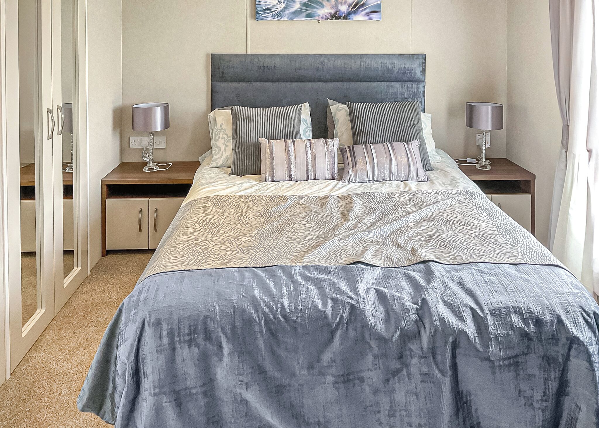 Une chambre à coucher avec un lit, deux tables de chevet, une armoire et un tableau au mur.