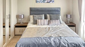 A bedroom with a bed, two nightstands, a wardrobe, and a painting on the wall. - 1 bedroom accommodation in Laurenkirk (Laurenkirk)