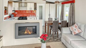 Un espacio habitable pequeño con chimenea, comedor y kitchenette.