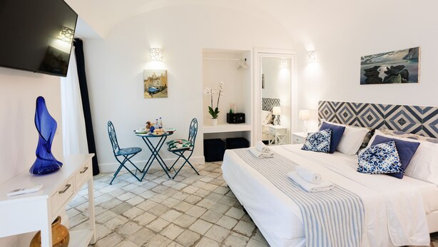 A hotel room with a bed, a desk, a chair, and a TV. - Suite Saint Michael (Capri)