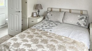 Un dormitorio con cama, mesita de noche, lámpara y una puerta.