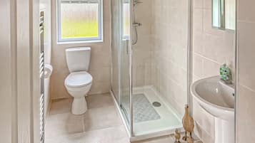 A bathroom with a toilet, shower, and sink.