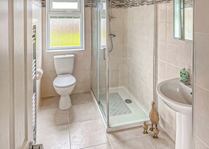 A bathroom with a toilet, shower, and sink.